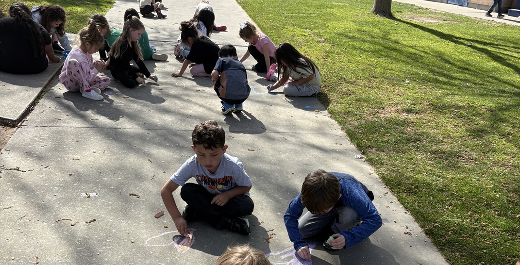 young children drawing with chalk on the sidewalk 