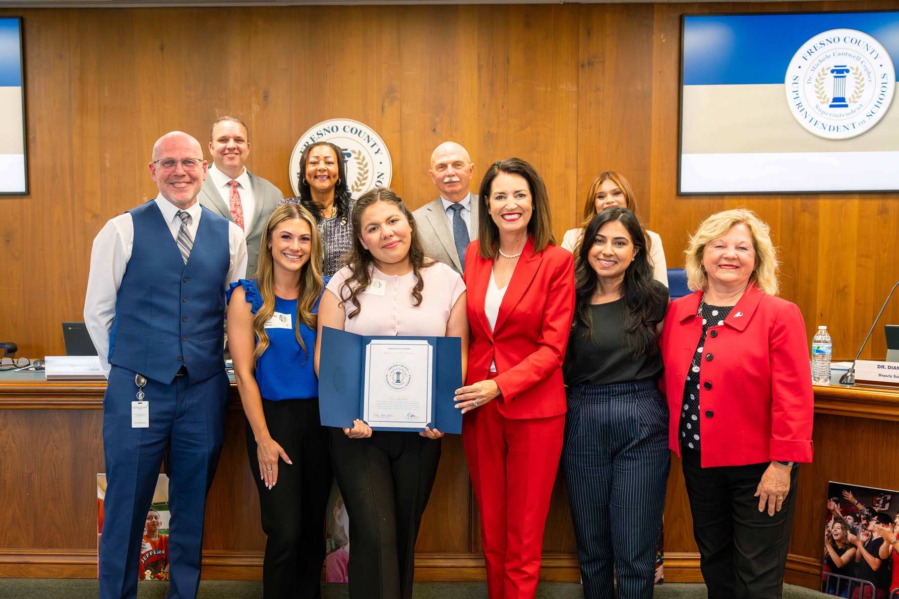 A girl stands with a certificate with her school teacher and disitrict superintendent, along with the County Superintendent of Schools, Dr. Michele Copher and the Board of education.