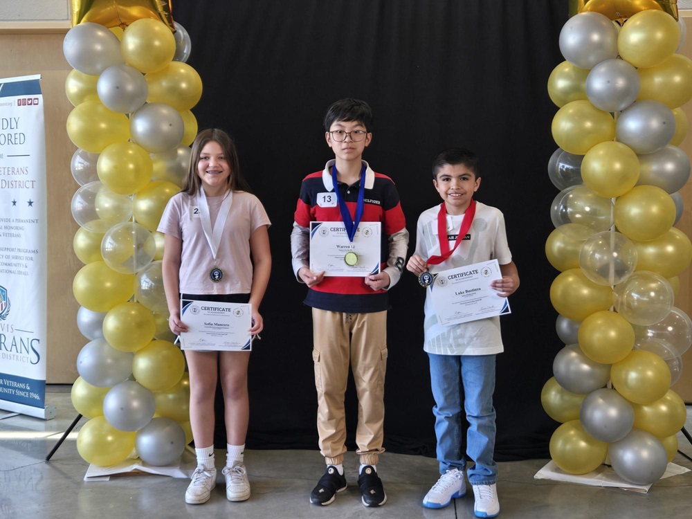 Three students standing with certificates of their accomplishments at the Spell Off. 