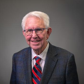 director, wearing gray suit with red and blue tie and glasses